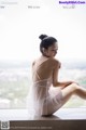 A woman in a white lingerie sitting on a window sill.