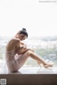 A woman in a white lingerie sitting on a window sill.