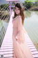 A woman in a pink dress standing on a bridge.