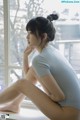 A woman sitting on a window sill looking out a window.