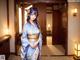 A woman in a blue kimono standing in a room.