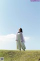 A woman standing on top of a lush green field.