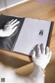 A person in white gloves holding a book on a table.