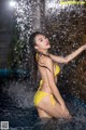 A woman in a yellow bikini standing in the water.