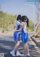 Two young women standing next to each other on a street.