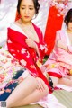 A woman in a kimono sitting on the ground next to another woman.