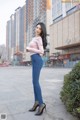 A woman in a pink top and blue jeans posing for a picture.