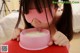 A little girl wearing a pink blindfold drinking milk from a bowl.