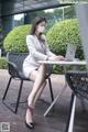 A woman wearing a face mask sitting at a table with a laptop.