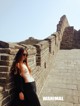 A woman leaning against a wall on the Great Wall of China.