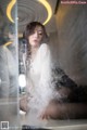 A woman sitting in front of a window with steam coming out of it.