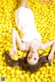 A woman laying in a pile of lemons.