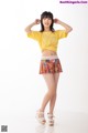 A woman in a yellow shirt and a colorful skirt.