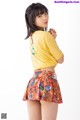 A woman in a yellow shirt and a colorful skirt.