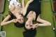 Two young women laying on top of a pool table.