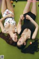 Two young women laying on a pool table.