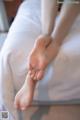 A woman is sitting on a bed with her feet up.