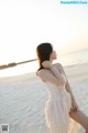 A woman in a white dress standing on a beach.