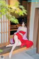 A woman in a red kimono sitting on a window sill.