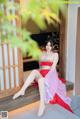 A woman in a red and pink dress sitting on a porch.