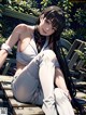 A woman sitting on a wooden bench in a park.