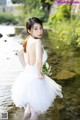 A woman in a white dress standing in a river.