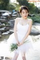 A woman in a white dress holding a bunch of flowers.