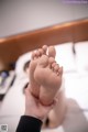 A person holding a pair of feet on a bed.