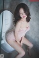 A woman in a pink lingerie sitting on a toilet.