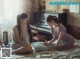 Two women sitting on a bed next to a piano.