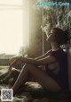 A woman sitting on a bed smoking a cigarette.