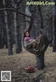 A woman sitting in a tree with a basket of apples.