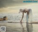 A woman in a white dress and hat standing in the water.