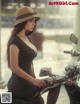 A woman in a polka dot dress and hat sitting on a motorcycle.