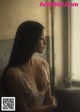 A woman in a white dress looking out a window.