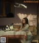 A woman sitting at a table with pigeons flying around her.