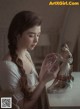 A woman in a white dress holding a figurine on a table.