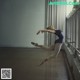 A young ballerina is jumping in the air in a dance studio.