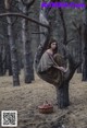 A woman sitting in a tree with a basket of apples.