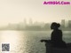 A woman sitting on a wall looking out over a body of water.