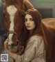 A woman standing next to a brown and white horse.