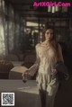 A woman standing next to a table with a glass of wine.