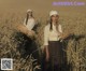 A woman standing in a field holding a bunch of wheat.