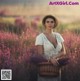 A woman in a field of purple flowers holding a basket.