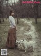 A woman walking two goats on a dirt road.