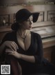 A woman in a black dress and hat sitting in front of a piano.