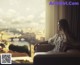 A woman sitting on a couch looking out a window.