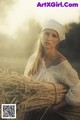 A woman in a white dress holding a bunch of wheat.