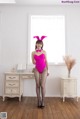 A woman in a pink bodysuit and bunny ears posing for a picture.