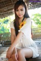 A woman in a white dress sitting on a wooden bench.